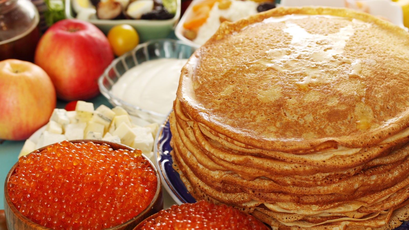 Румяные тонкие блины на столе с красной икрой на Масленицу