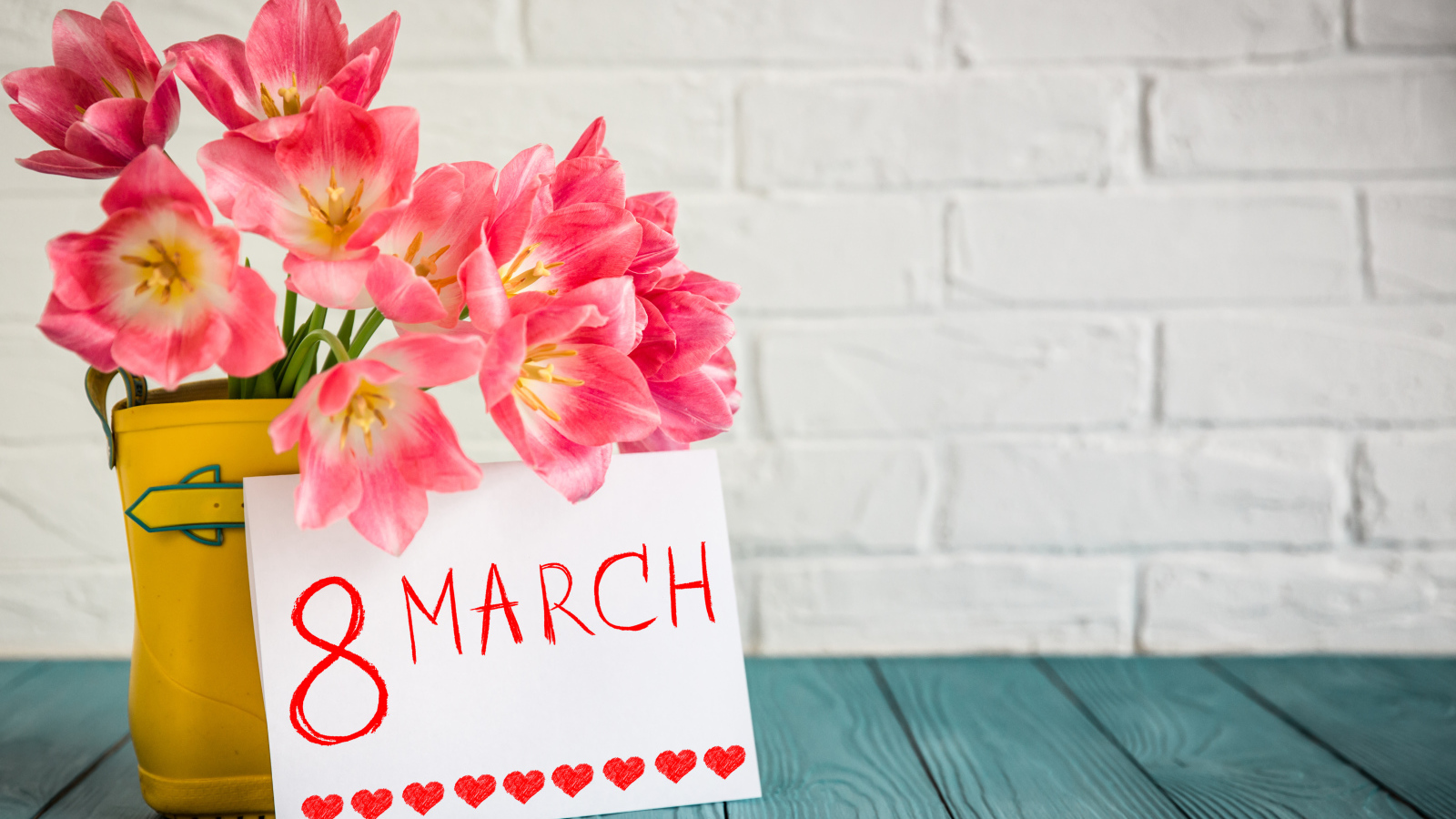 Букет тюльпанов и открытка на фоне стены на 8 марта