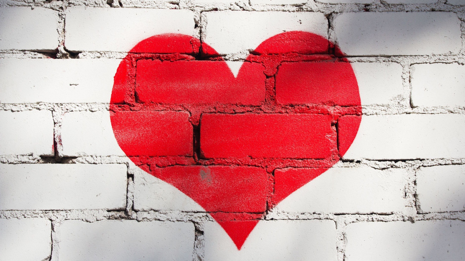 Большое красное сердце нарисовано на кирпичной стене
