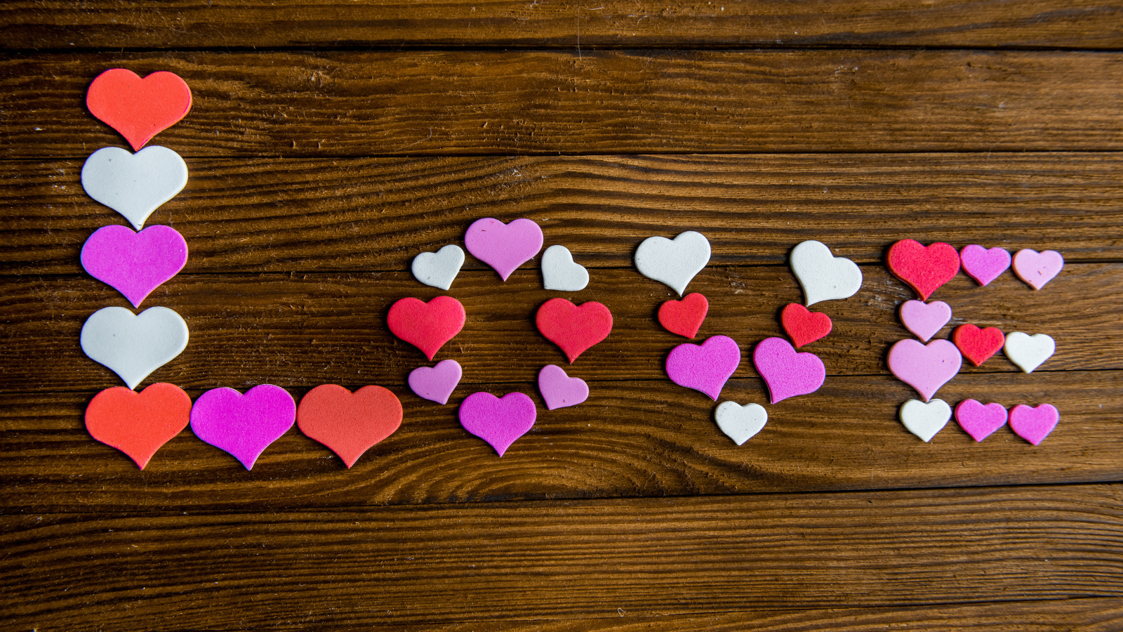 Надпись любовь из разноцветных сердец на деревянном столе