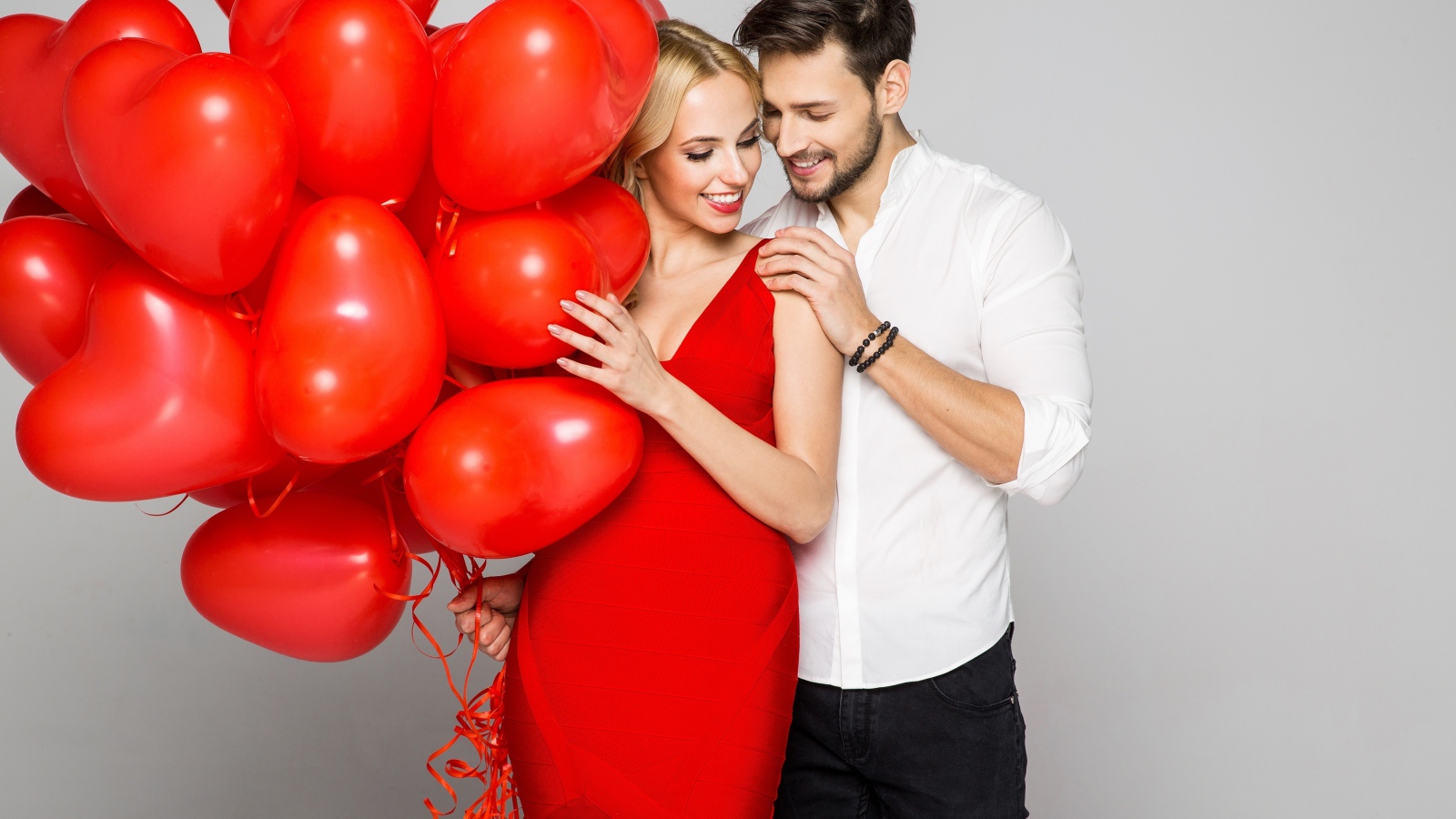Влюбленная пара с красными воздушными шарами в форме сердца
