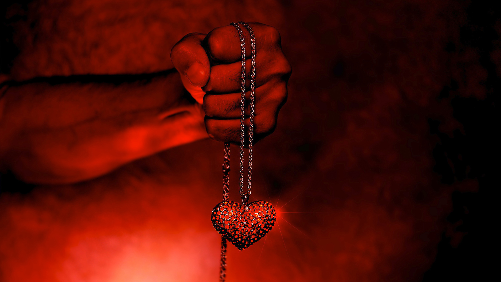 Pendant with a heart on a chain in a man's hand