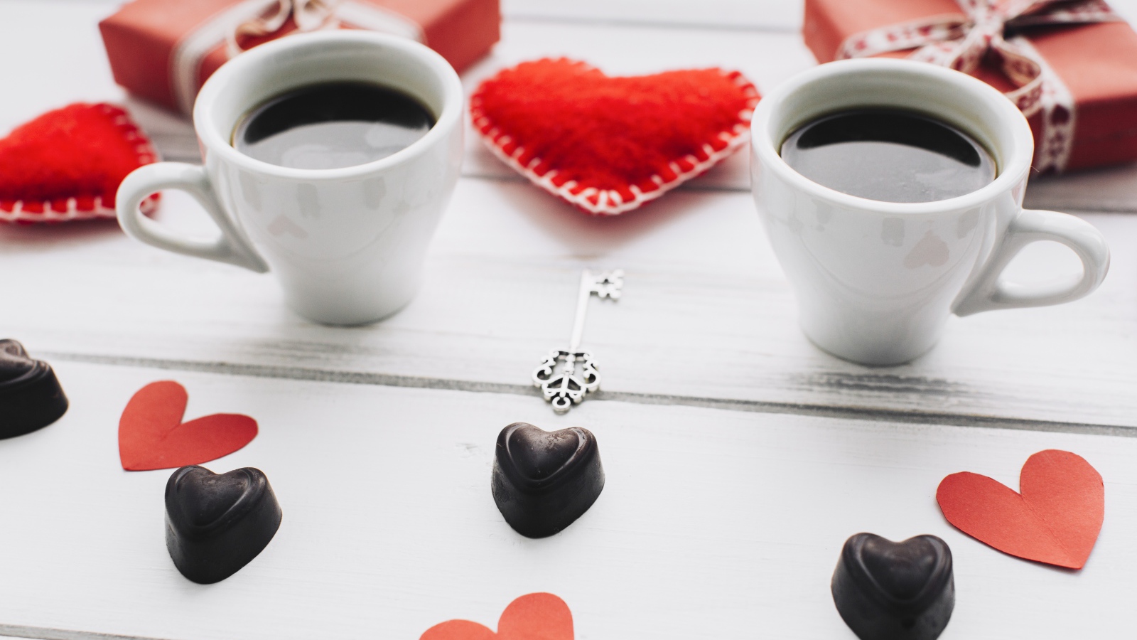 Two cups of coffee on the table with gifts, sweets and hearts