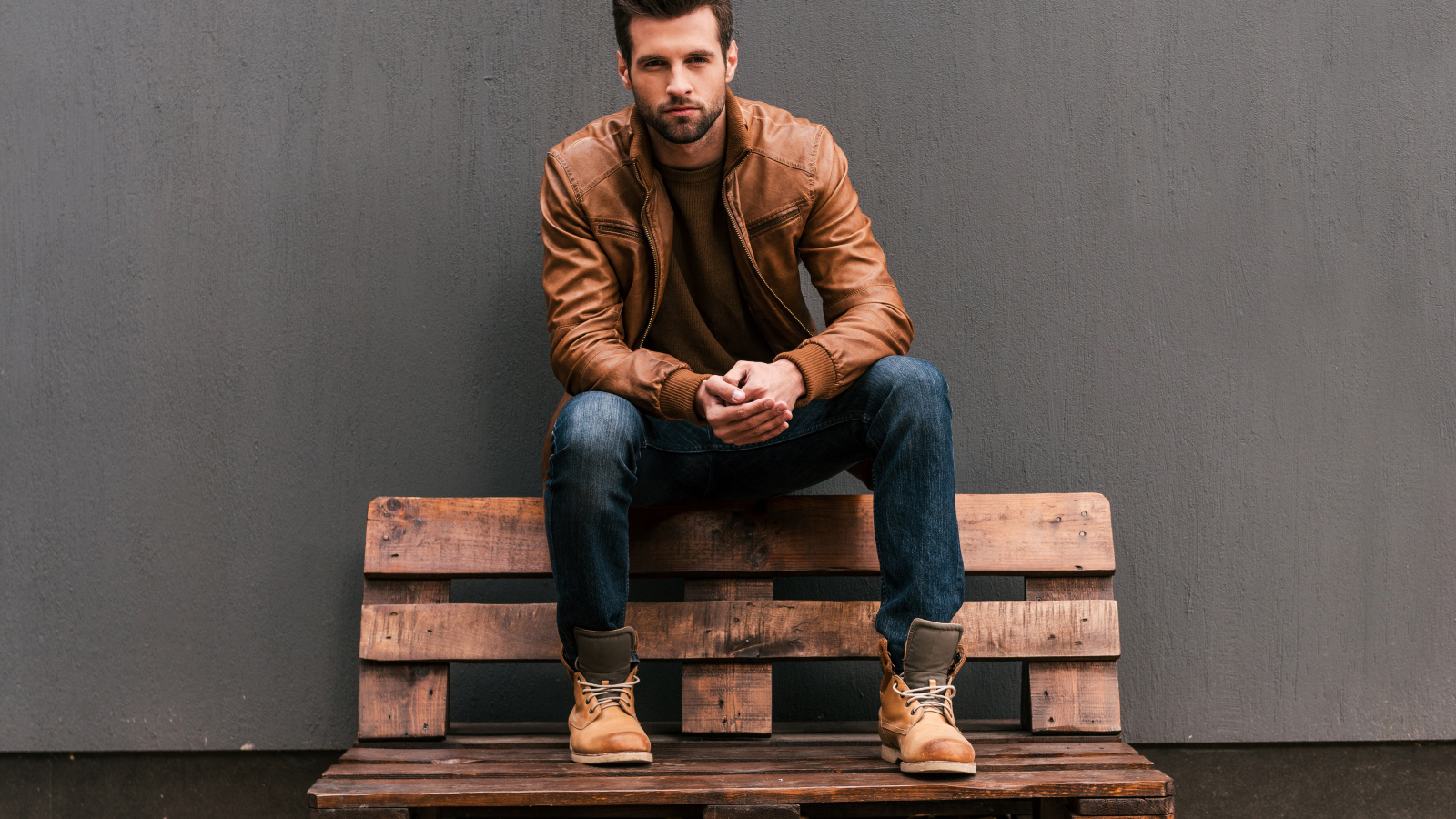 Young handsome man sitting on a wooden bench