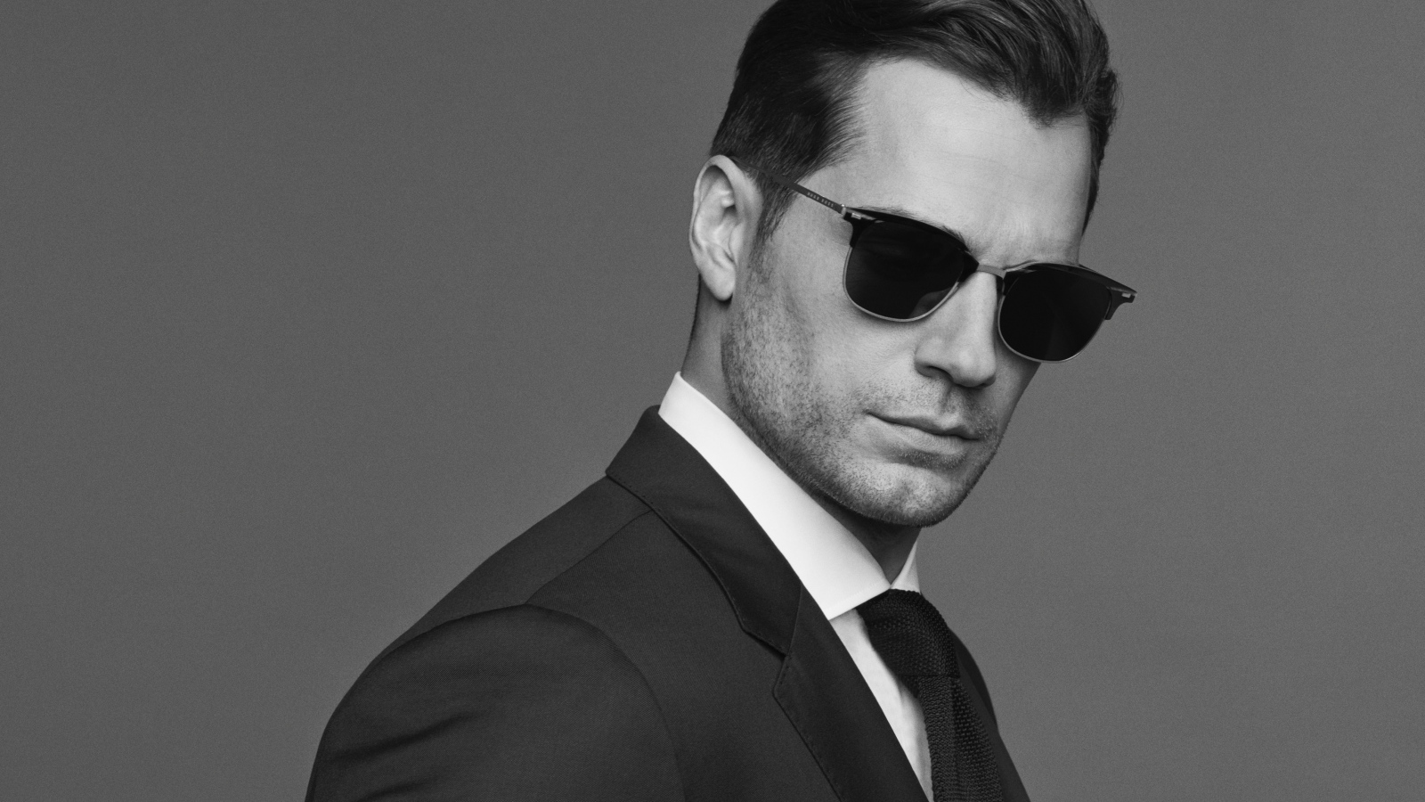 Английский актер Генри Кавилл в черных очках, черно белое фото 