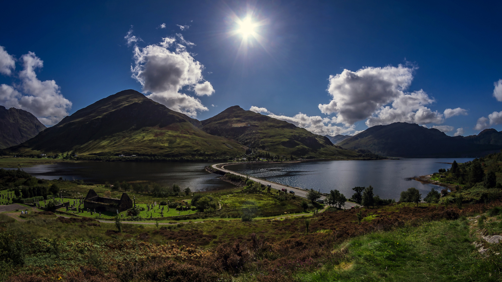 Яркое солнце в голубом небе над горами у реки