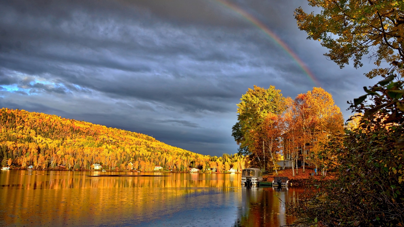 Радуга в пасмурном небе над озером у осеннего леса