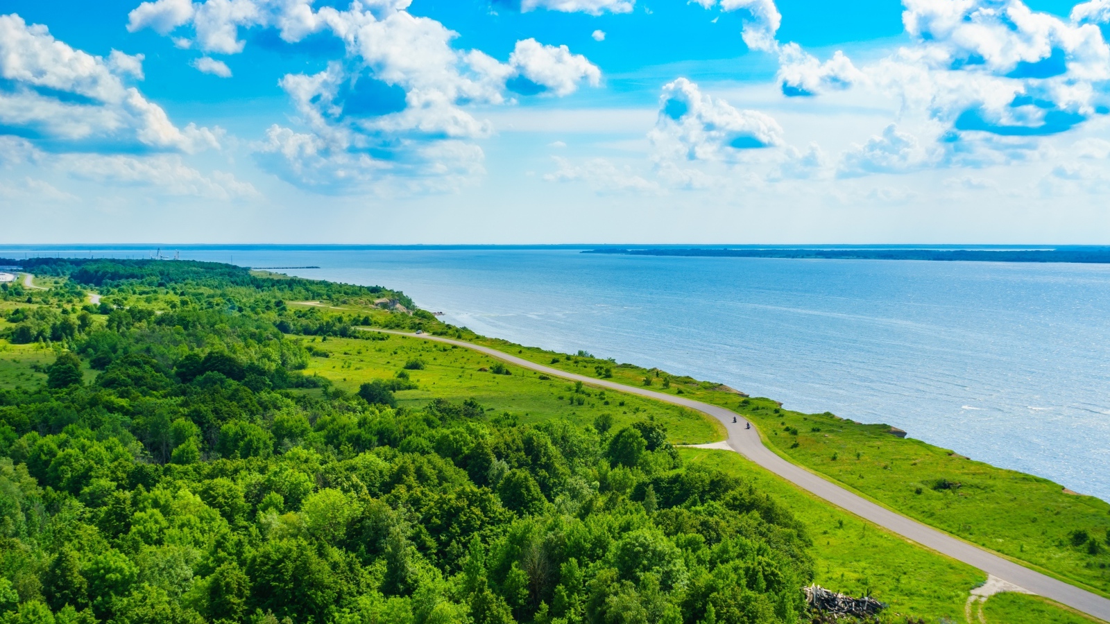 Дорога через побережье вдоль моря под голубым небом с белыми облаками