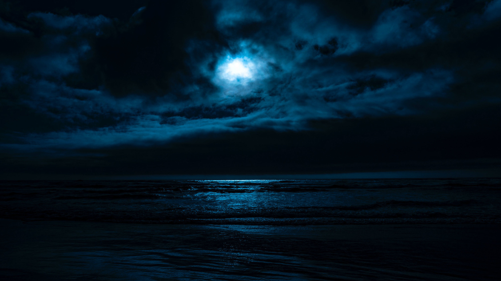 The moon in the cloudy sky over the sea at night