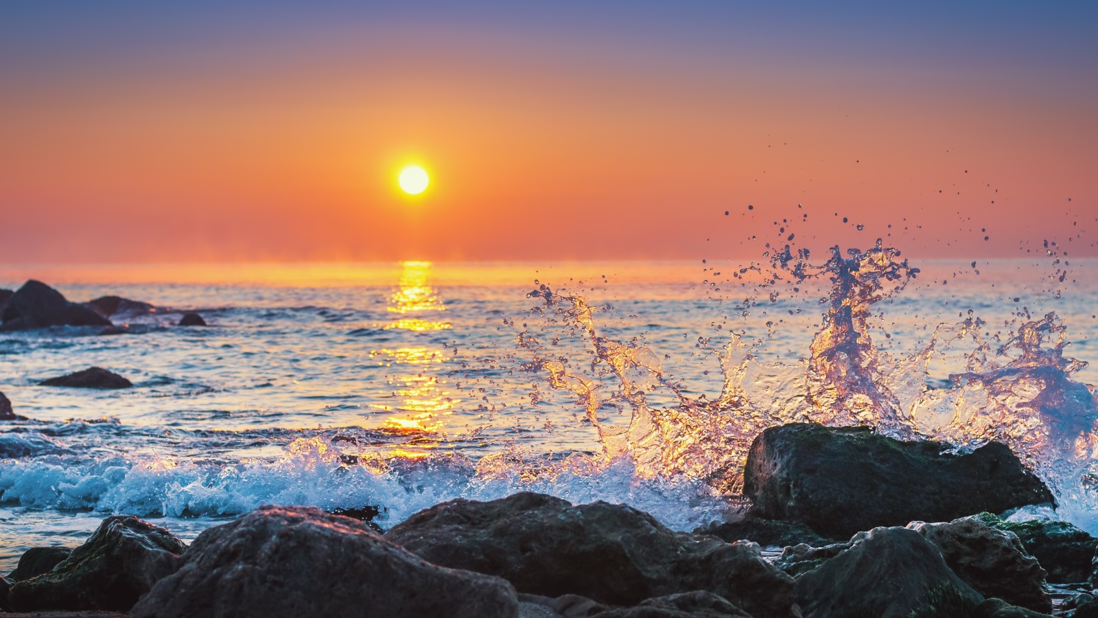 Волны бьются о камни на морском побережье на закате