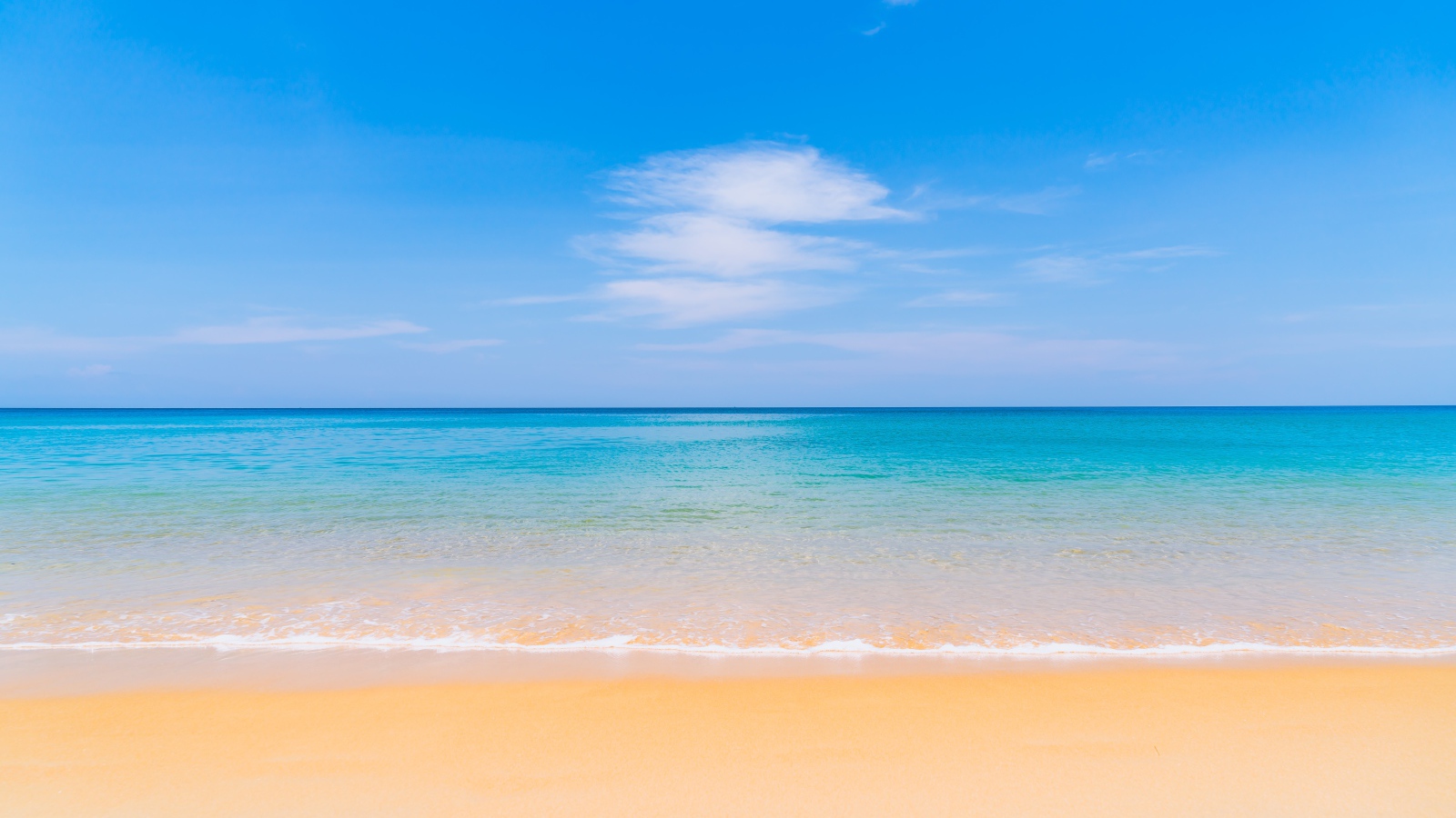 Желтый песок у лазурного океана под голубым небом