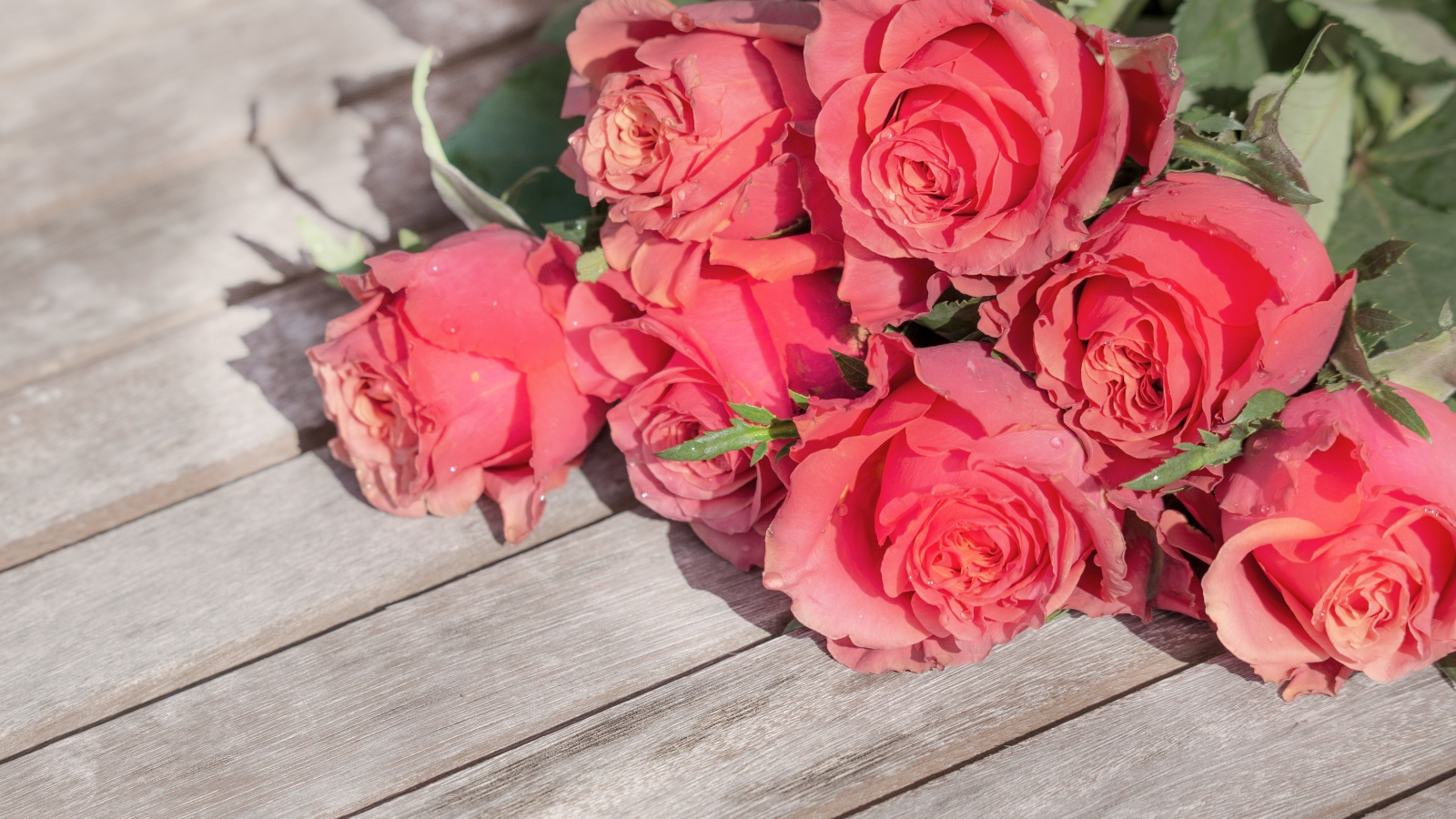 Букет розовых роз лежит на деревянной поверхности