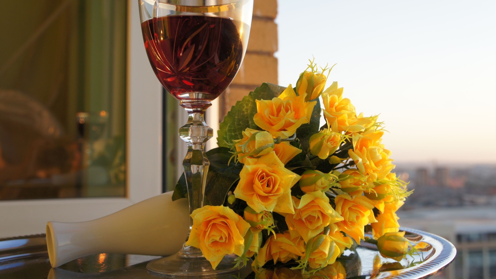 Букет желтых роз на столе с бокалом вина