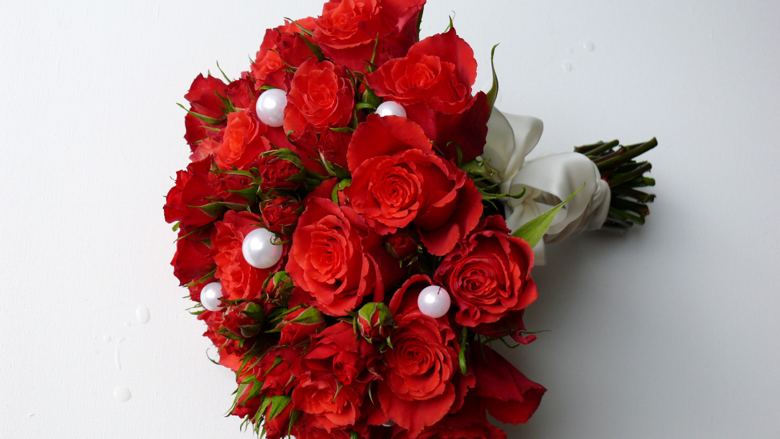 Красивый букет красных роз с жемчужными бусинами на сером фоне