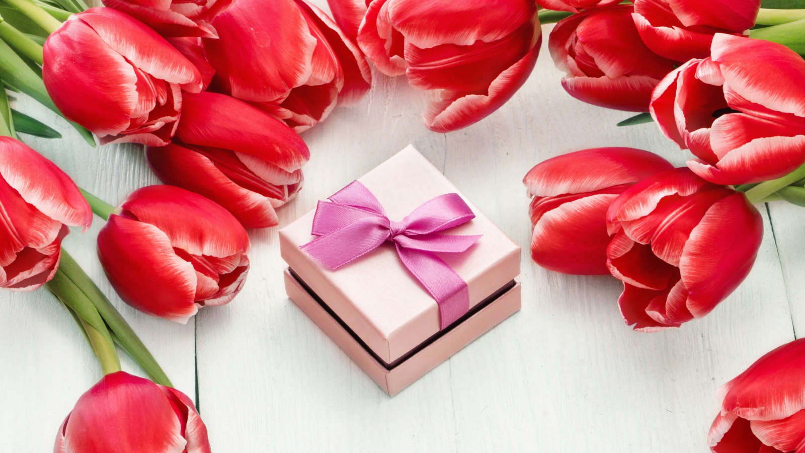 Красные тюльпаны на деревянной поверхности с подарком