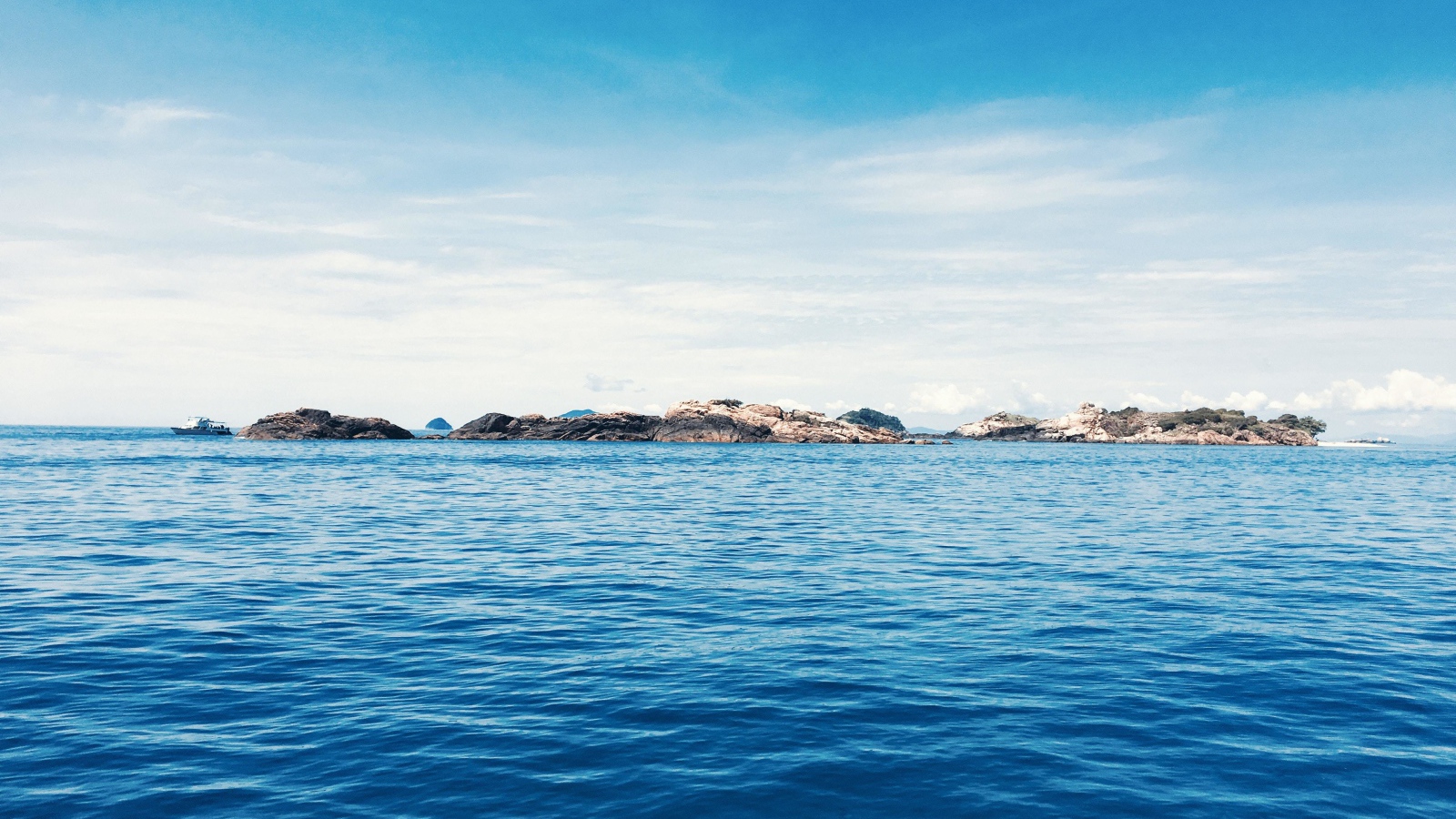 Спокойное синее море со скалами на горизонте