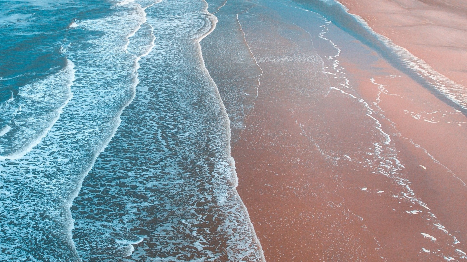 Нежные белые волны омывают песчаный берег океана 