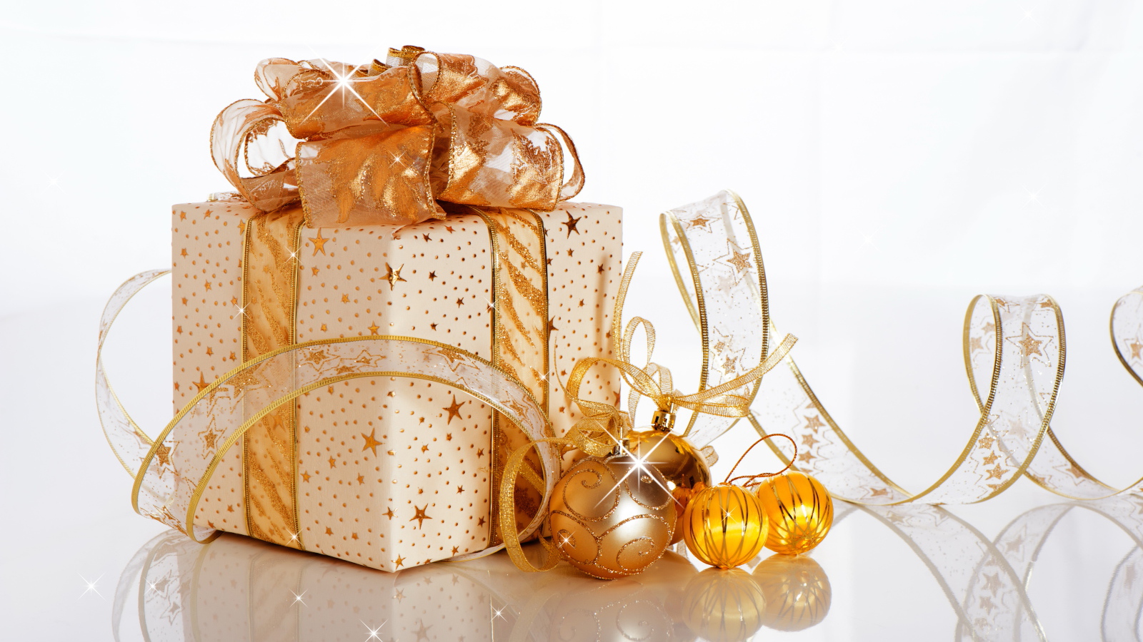 Красивый подарок с лентой и елочными шарами на белом фоне на Новый год 2019