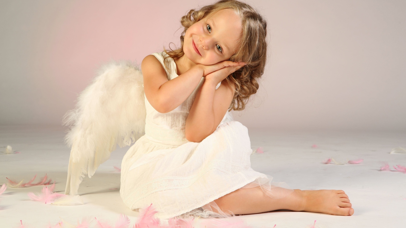 Милая маленькая девочка в белом платье с крыльями ангела
