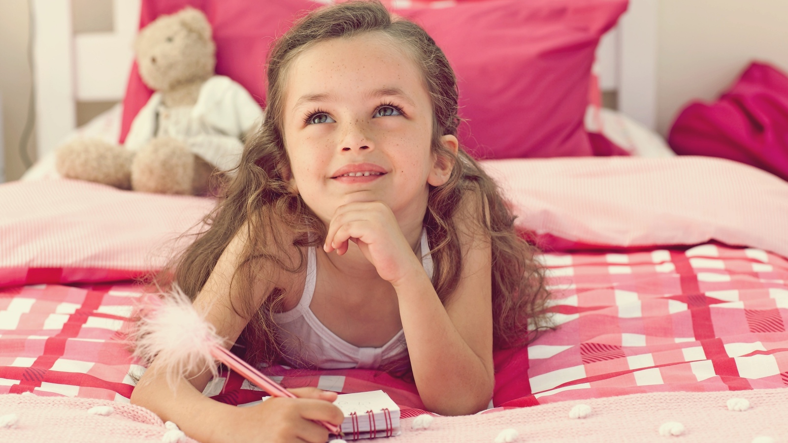 Замечтавшаяся маленькая девочка лежит на кровати