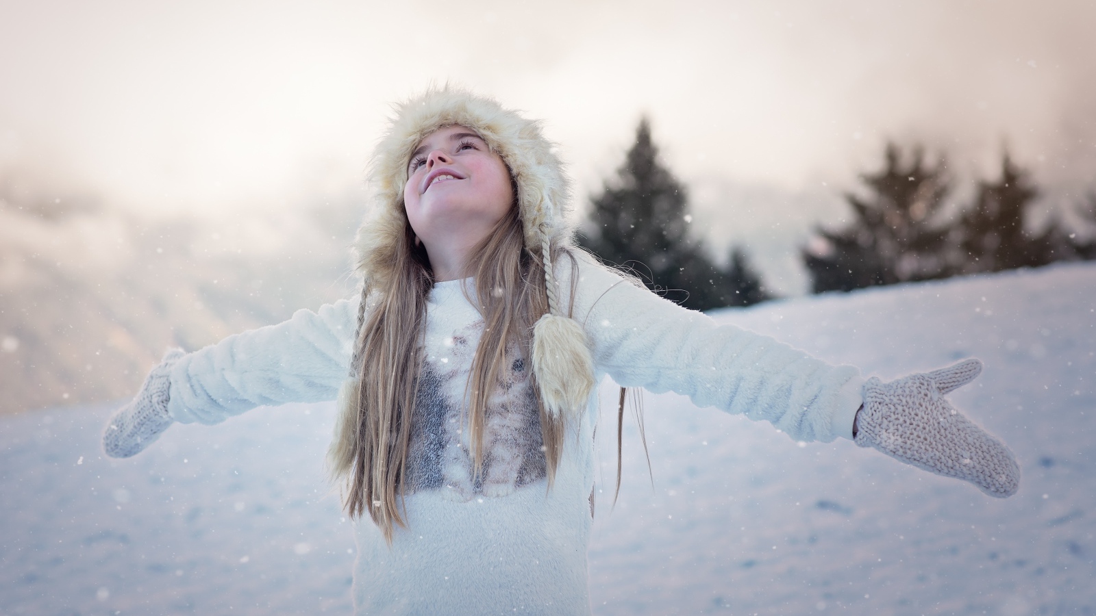Девочка в белой шапке радуется снегу