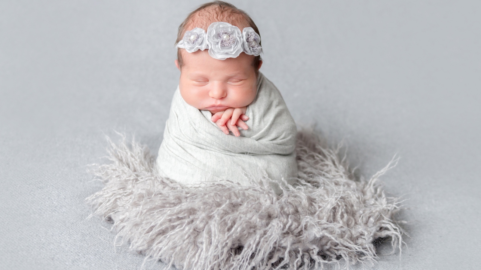 Маленький спящий младенец на сером фоне