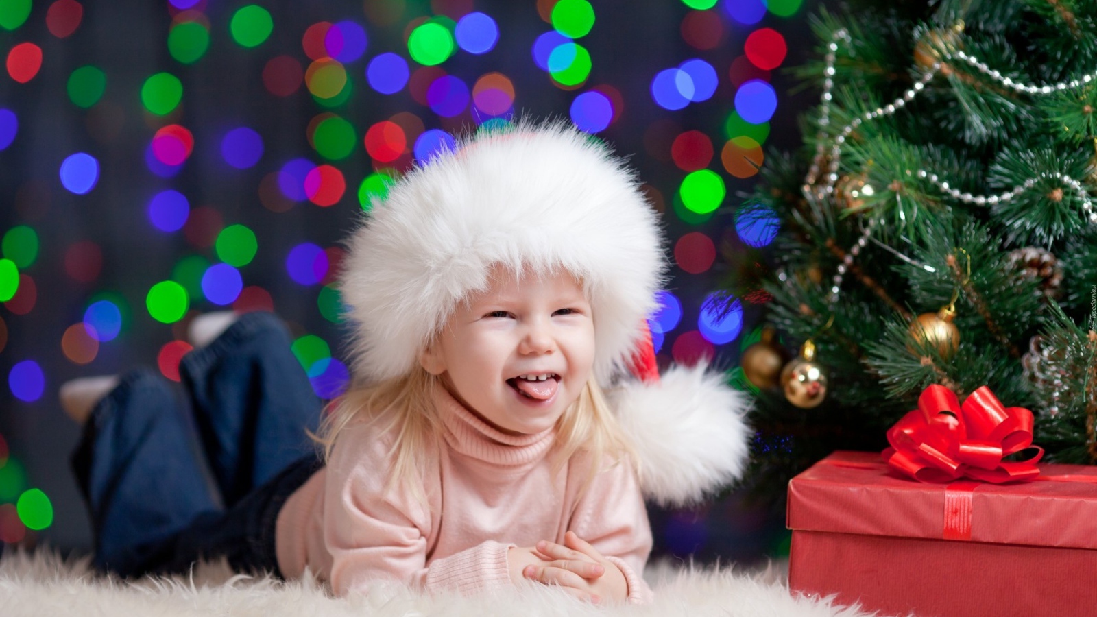 Смешная девочка в новогодней шапке у елки