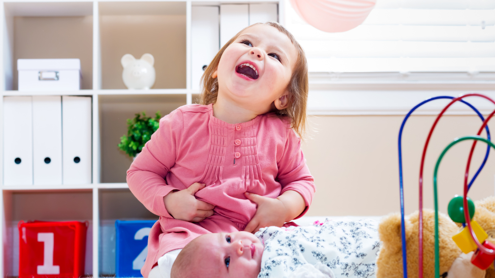 Смеющаяся маленькая девочка с младенцем