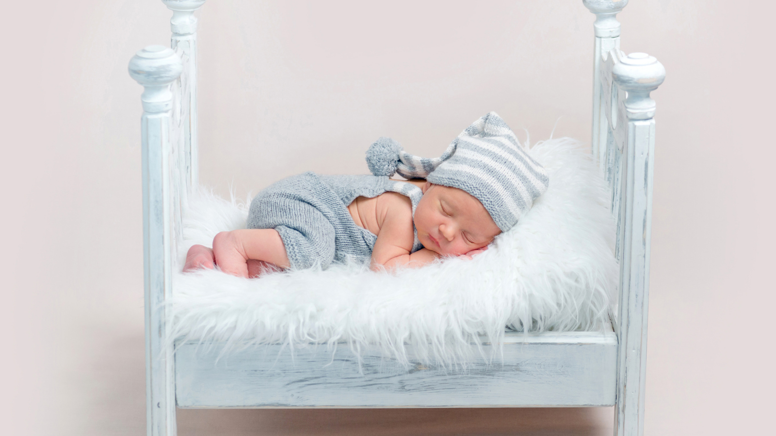 Маленький грудной ребенок спит в маленькой кроватке