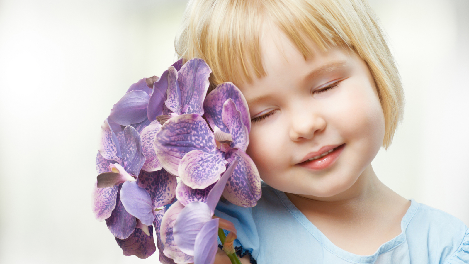 Маленькая девочка блондинка с цветами орхидеи