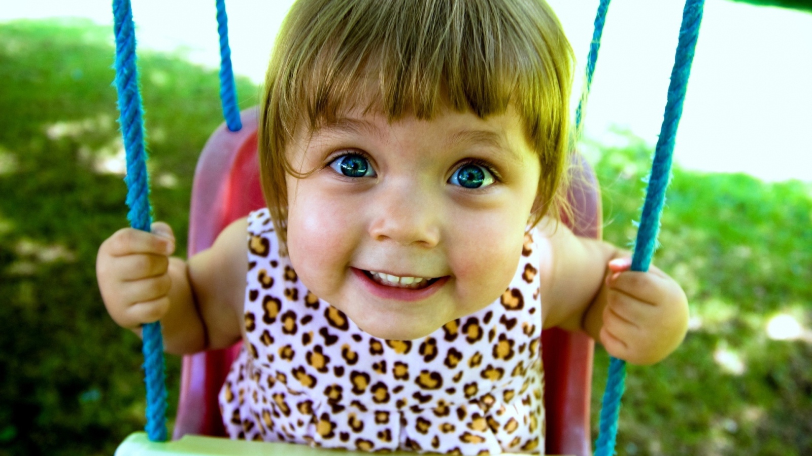 Маленькая голубоглазая девочка на качели