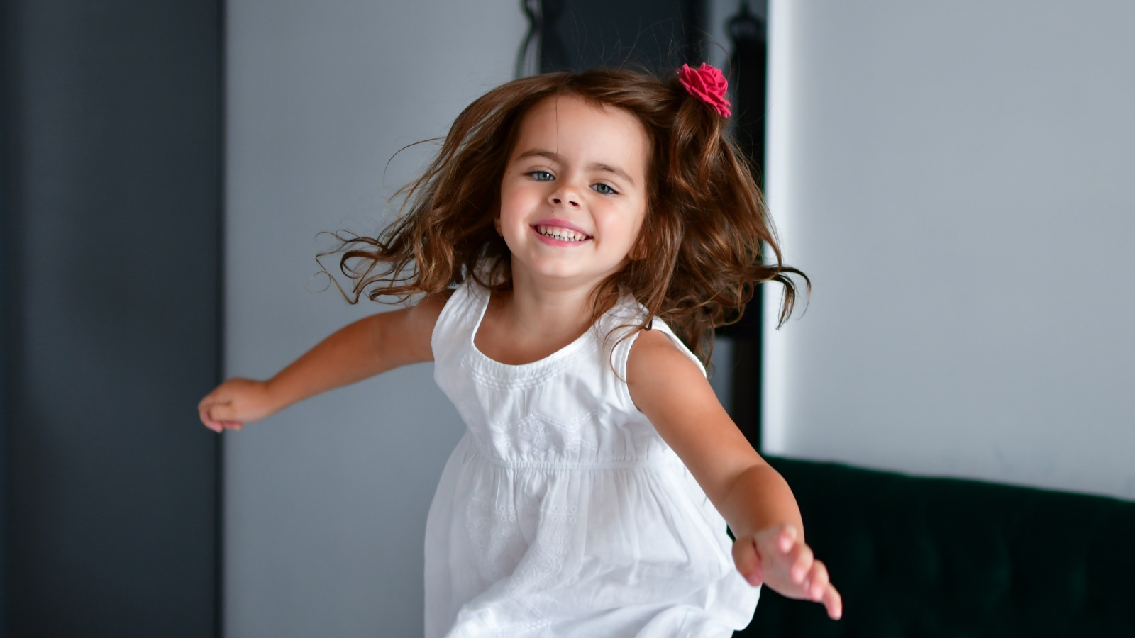 Маленькая веселая девочка в белом платье