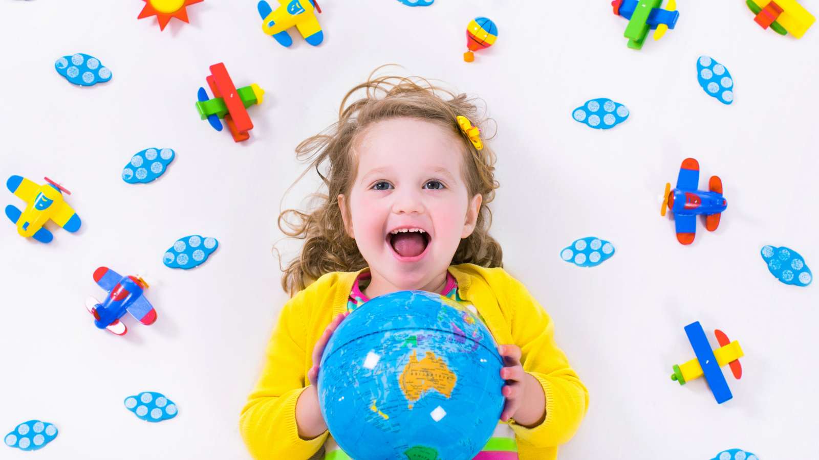 Маленькая веселая девочка с глобусом в руках 