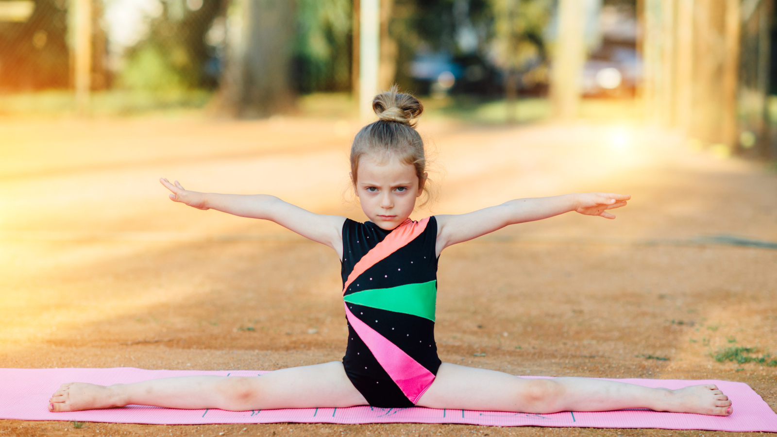 Маленькая девочка гимнастка сидит на шпагате 