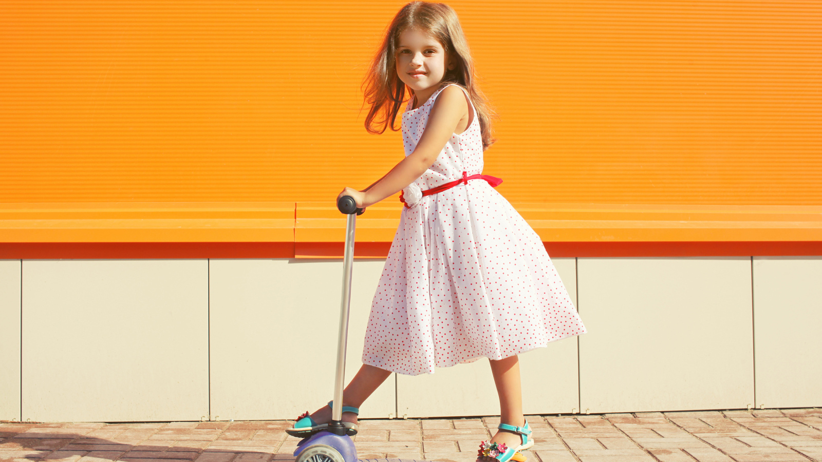 Маленькая девочка в платье на самокате 