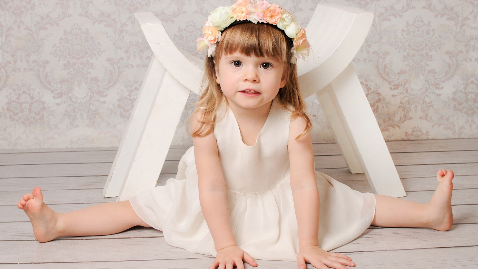 Маленькая девочка сидит на шпагате