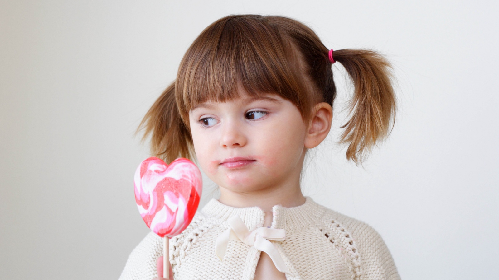 Маленькая девочка с большой конфетой на палочке