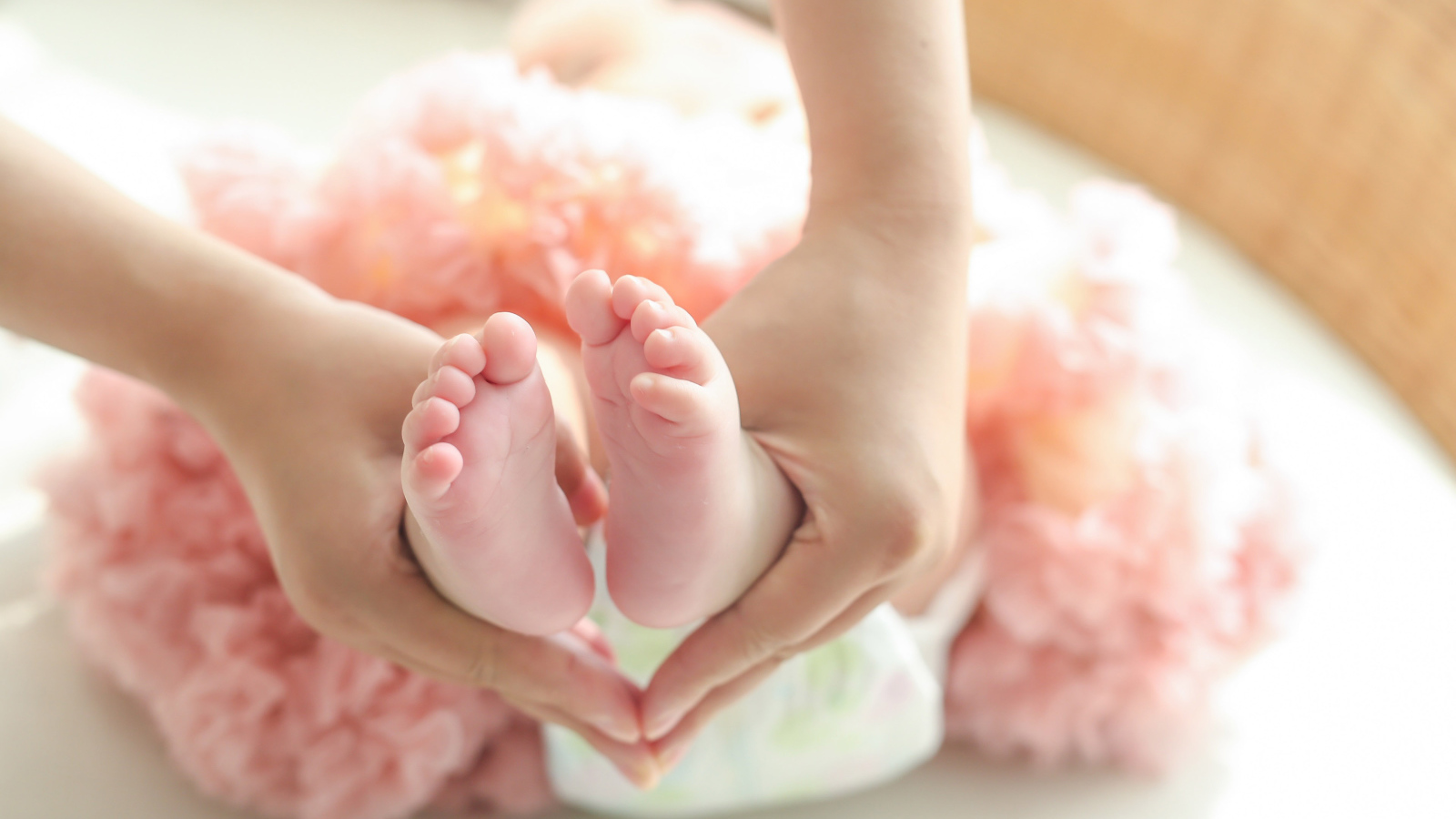 Маленькие ножки новорожденного в ладонях у мамы 
