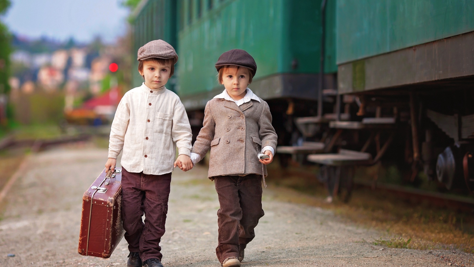 Два маленьких мальчика с большим чемоданом у поезда