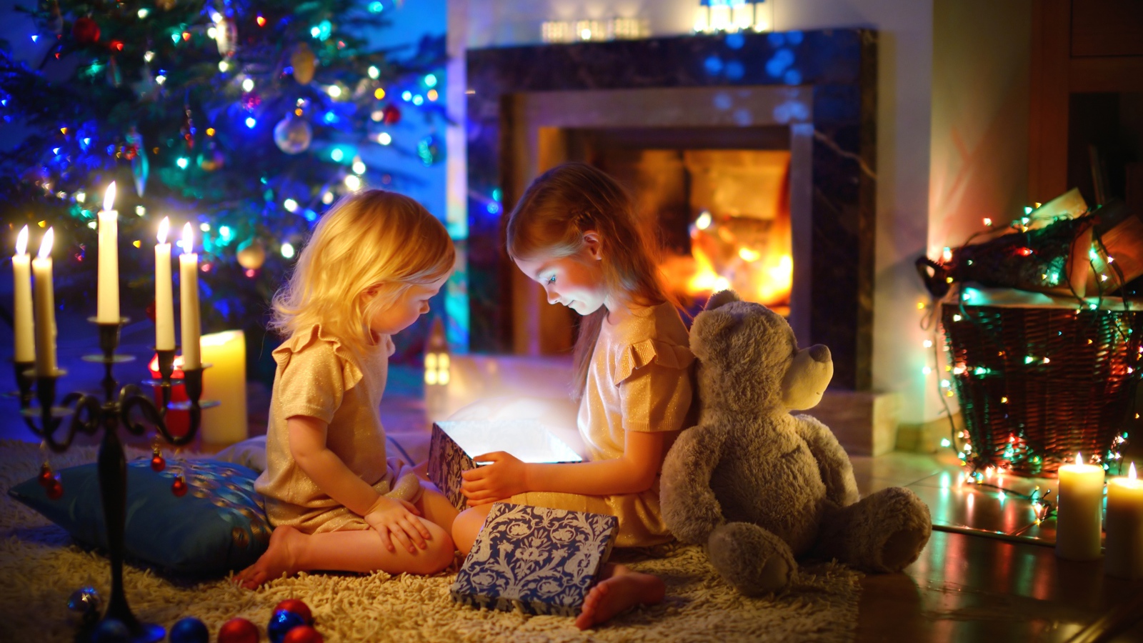 Две маленькие девочки с игрушками у камина