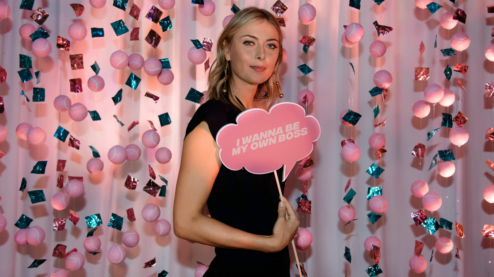 Теннисистка Мария Шарапова с табличкой в руках на розовом фоне