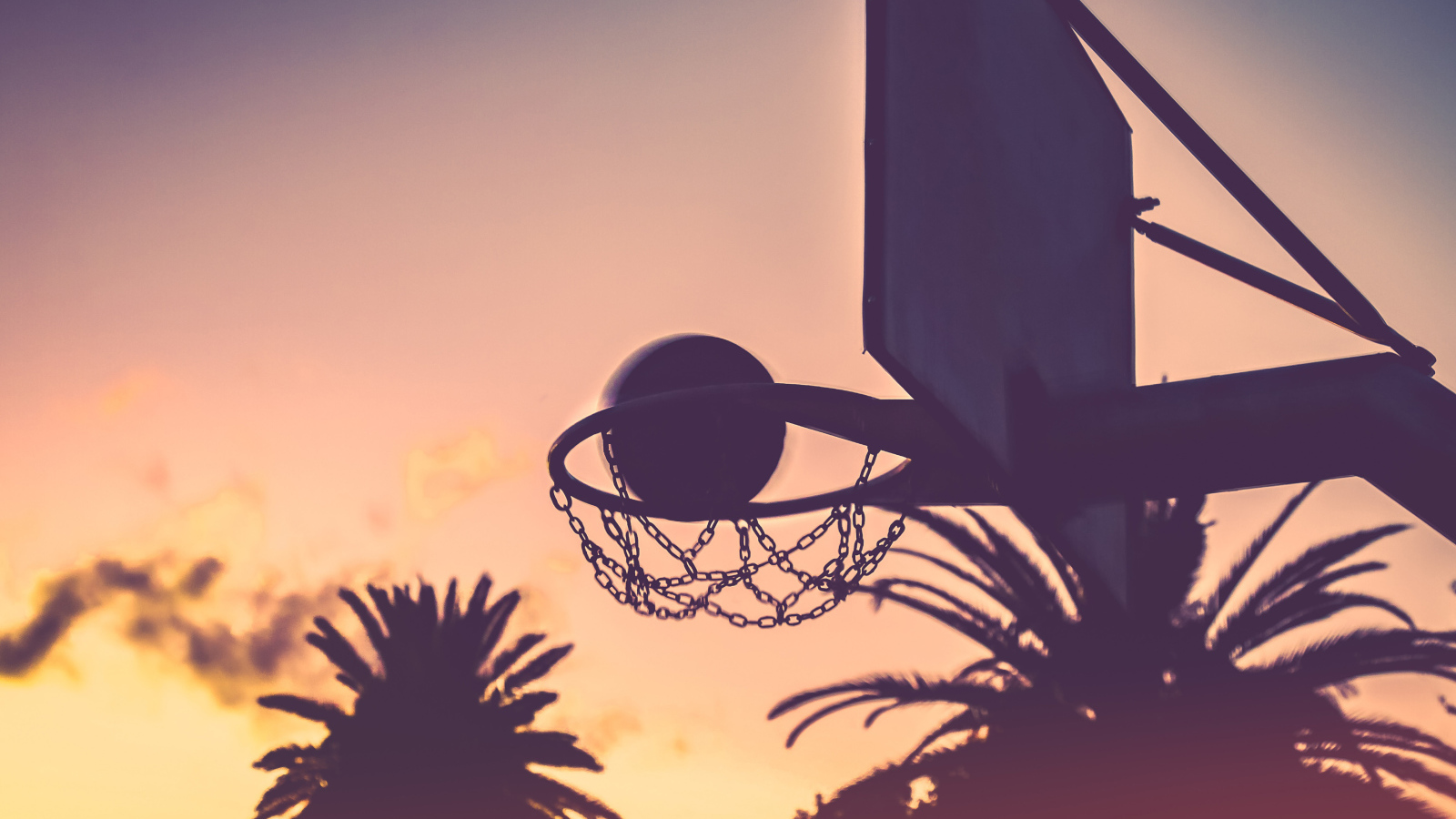 Баскетбольное кольцо с мячом на закате