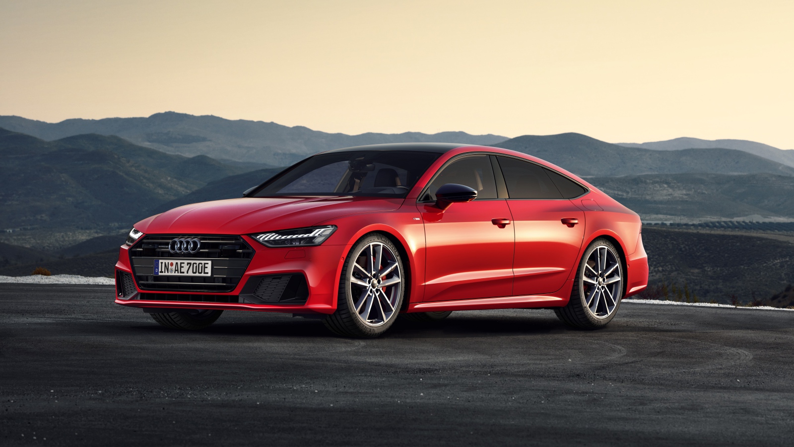 Красный автомобиль Audi A7 Sportback 55 TFSI E Quattro S Line 2019 года в горах