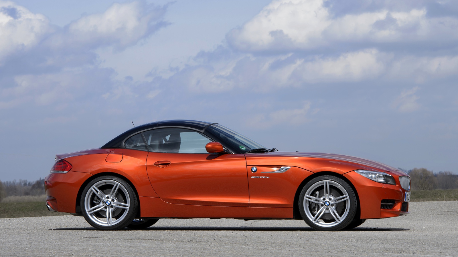 Оранжевый автомобиль BMW Z4 на фоне красивого неба