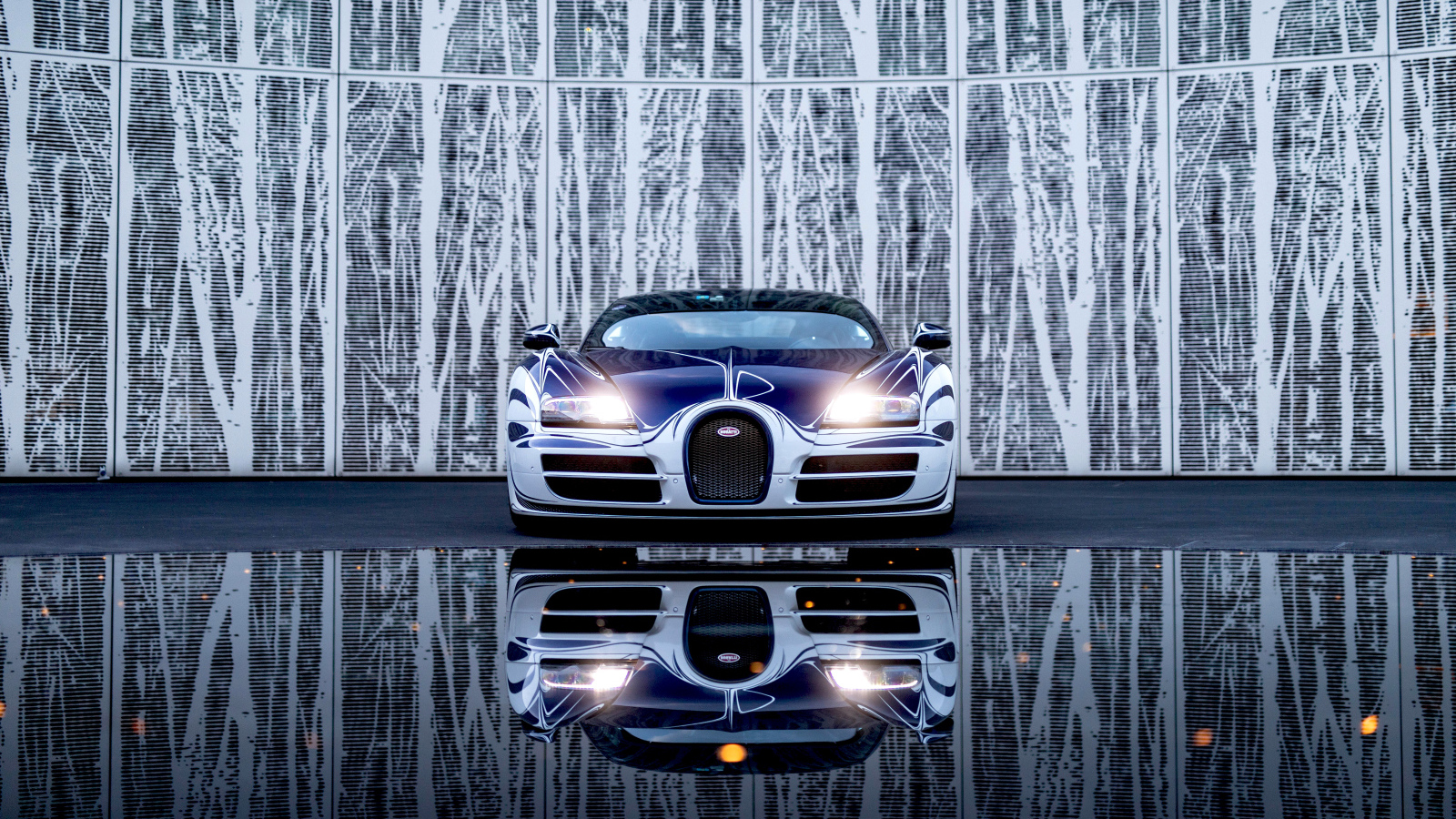 Автомобиль Bugatti Veyron Grand Sport Roadster отражается в зеркальной поверхности 