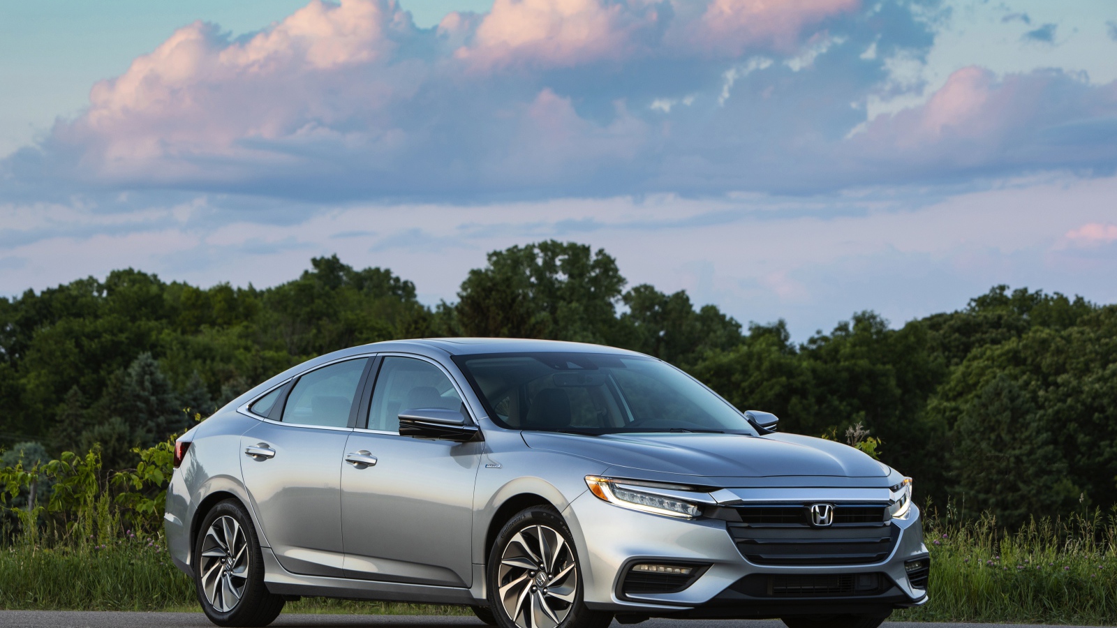 Серебристый автомобиль Honda Insight на фоне леса