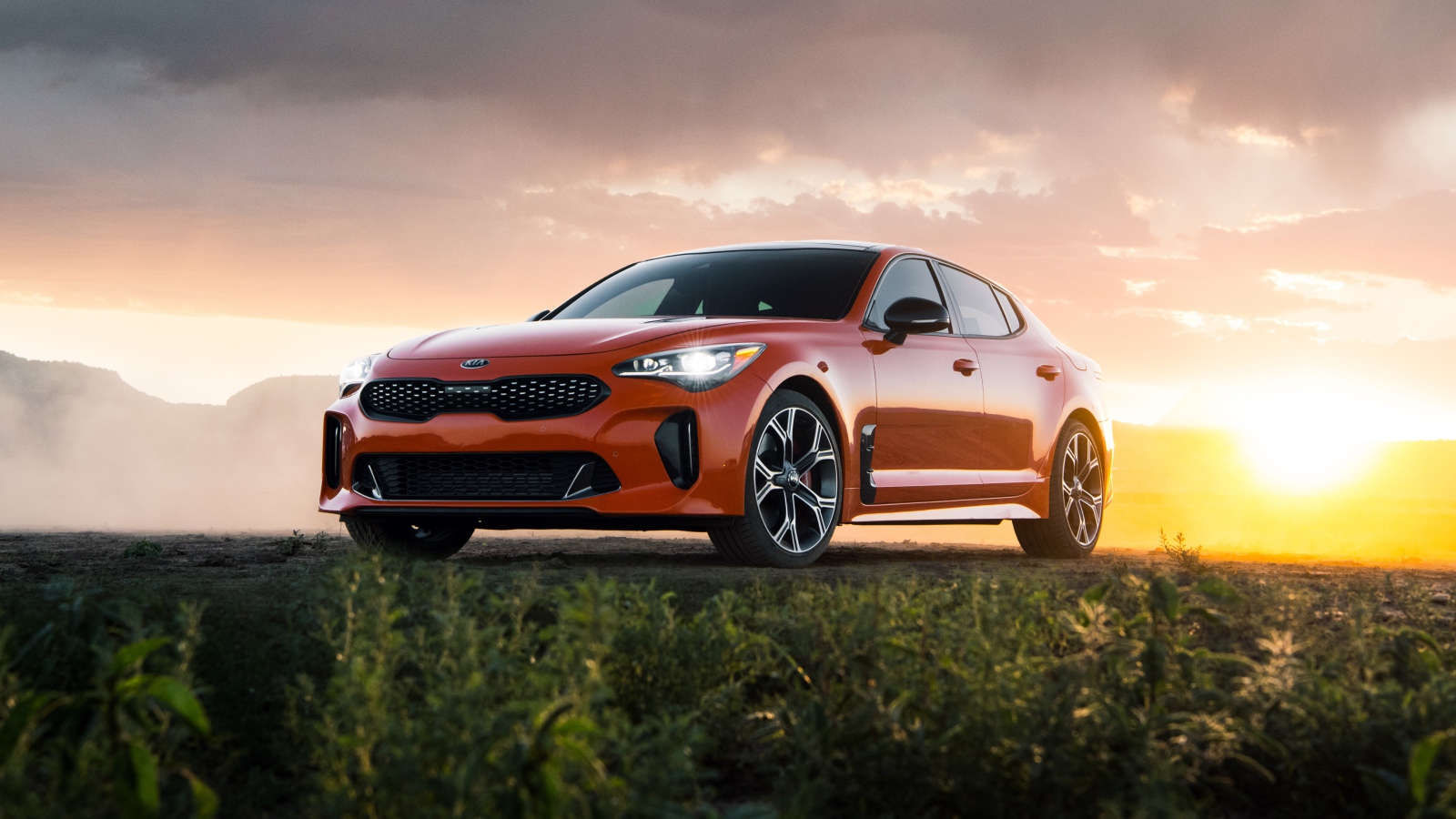 Оранжевый автомобиль  Kia Stinger GTS, 2020 года на закате