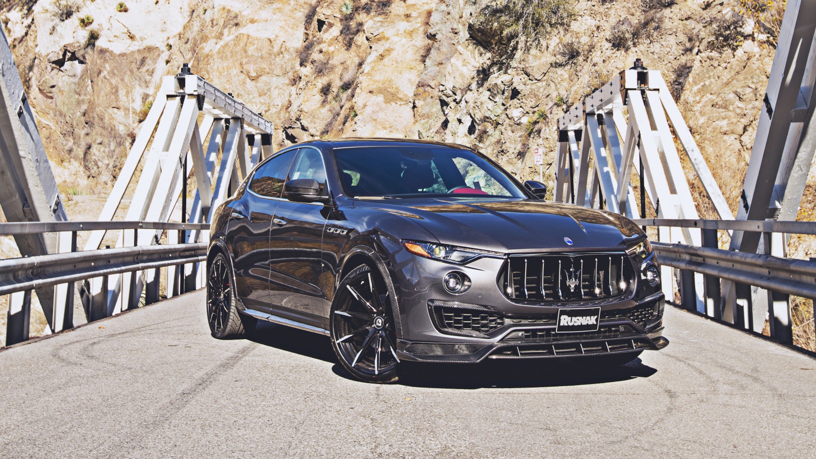 Внедорожник Maserati Levante на мосту на фоне гор