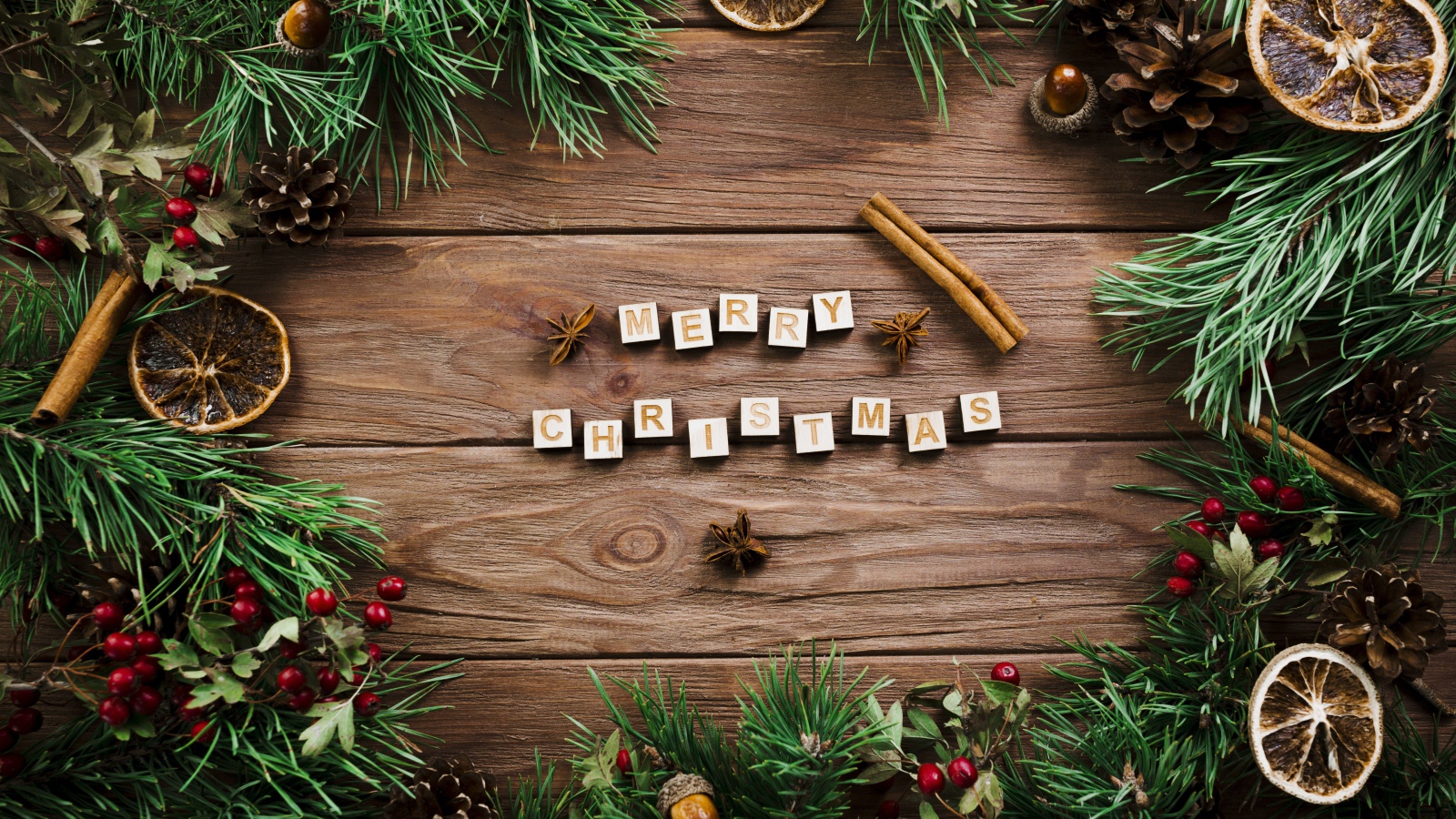 Надпись Merry Christmas на деревянном столе с еловыми ветками 