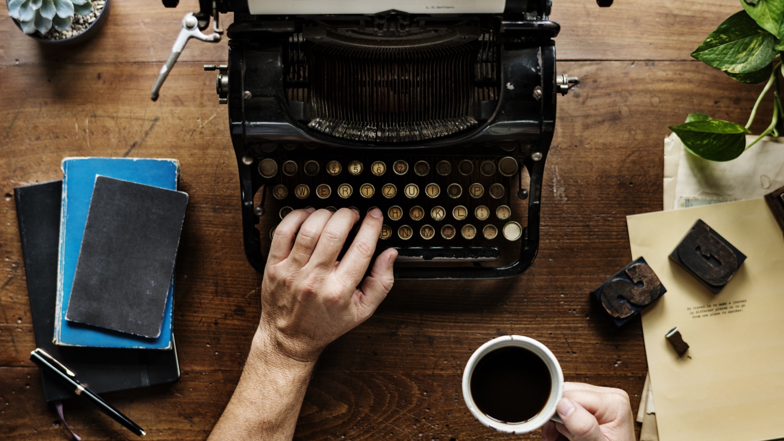 Мужчина с чашкой кофе в руке печатает на старой печатной машинке 